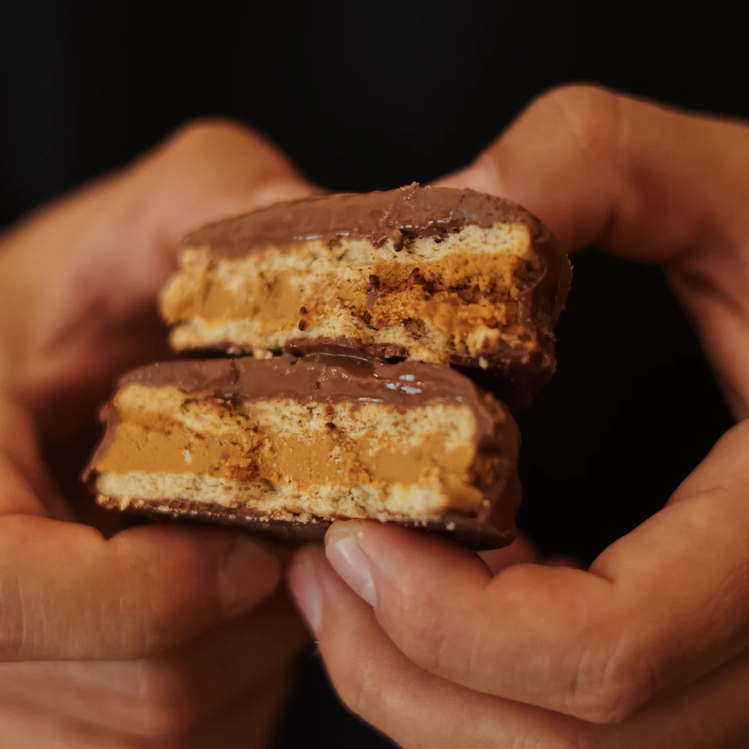 Alfajor de chocolate aberto em duas metades, revelando biscoito e doce de leite